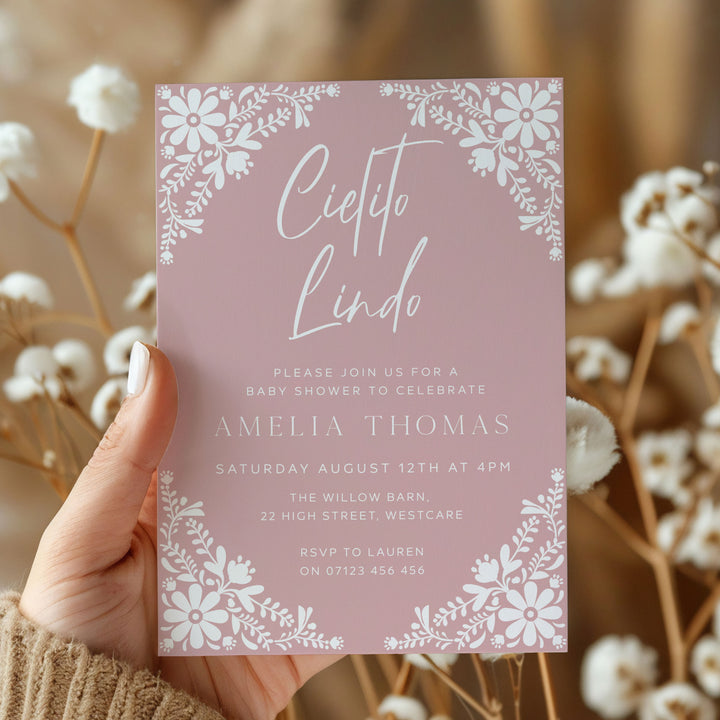 Elegant baby shower invite in dusty rose with Cielito Lindo script and white folk art flowers, ideal for a girl’s party.