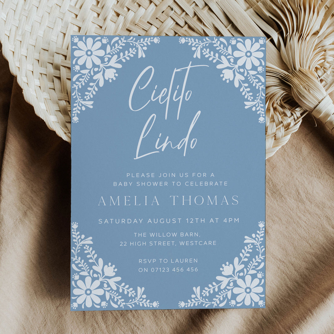 Blue Cielito Lindo baby shower invitation with white floral border, perfect for a fiesta-themed celebration for moms-to-be.