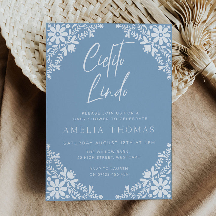 Blue Cielito Lindo baby shower invitation with white floral border, perfect for a fiesta-themed celebration for moms-to-be.