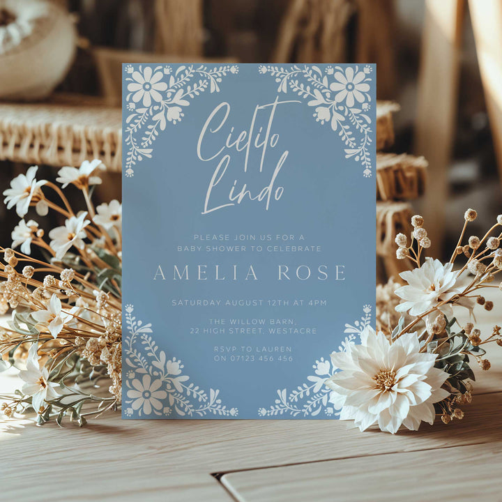 Cielito Lindo baby shower invitation featuring soft blue background and delicate white folk art flowers, great for summer events.