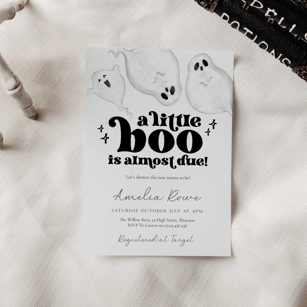 Halloween-themed baby shower invitation with ghosts on a textured surface