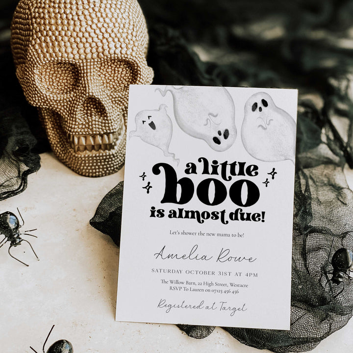 Halloween-themed baby shower invitation with ghosts and a skull in the background