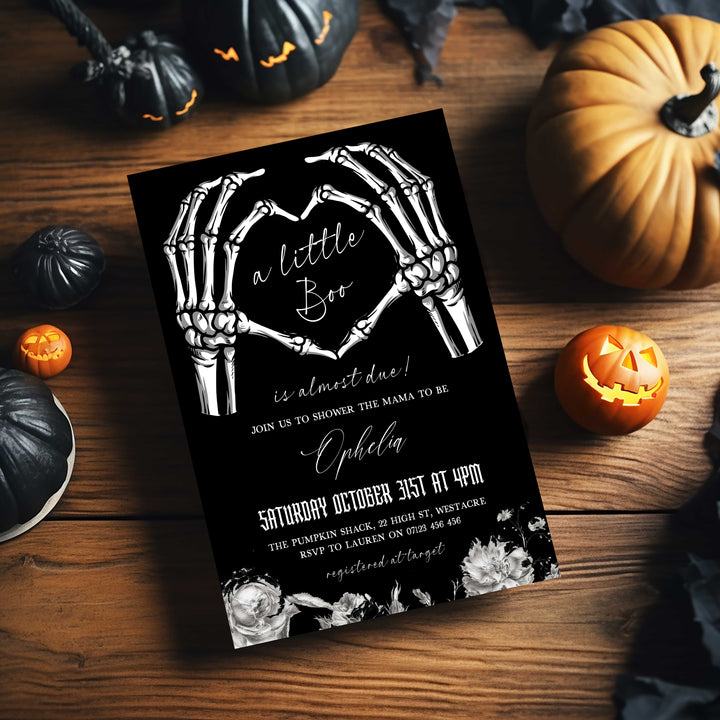 Halloween baby shower invitation with skeleton hands forming a heart and ‘A Little Boo is Almost Due’ text for spooky celebration.