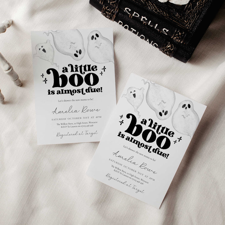 Halloween-themed baby shower invitations with ghosts and text on a neutral background.