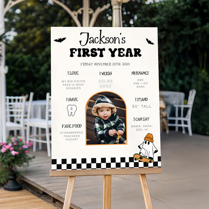 First birthday sign with custom baby details, plaid outfit photo, and fall floral backdrop, great for keepsake or party display.