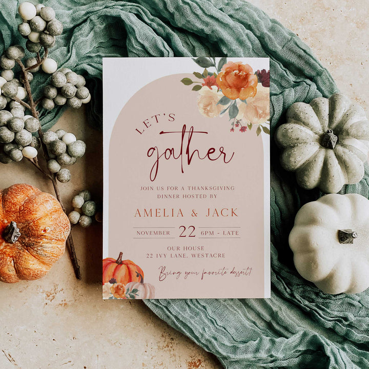 Thanksgiving dinner invitation card held in hand, featuring floral and pumpkin illustrations, perfect for hosting a fall gathering.
