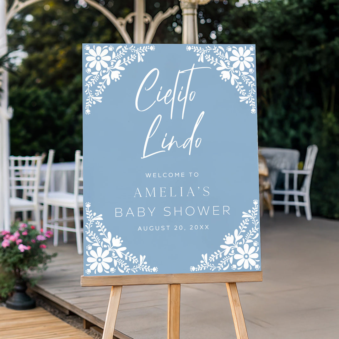 Fiesta-inspired baby shower sign with white folk art flowers and elegant calligraphy on a blue background.