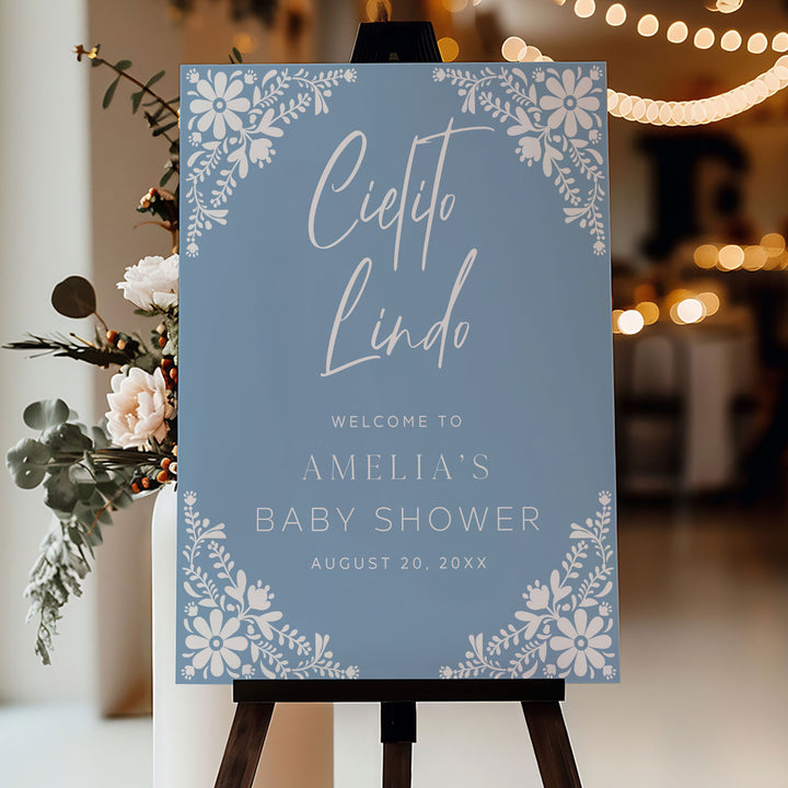 Large blue welcome sign for a Cielito Lindo baby shower, displayed on wooden easel at an outdoor garden venue.